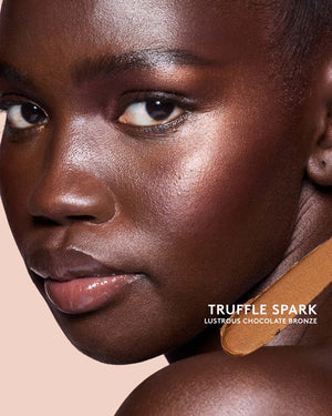 Deep skin toned model wearing match stix shimmer in shade Truffle Spark.