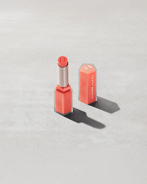 Open shot of Gloss Bomb Stix Shimmer in shade See You in Maui on a concrete background.