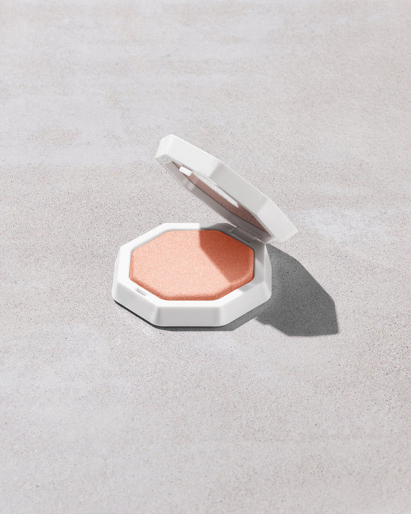 Open product shot of Demi'glow Light-Diffusing Highlighter in shade Tutu Much on a concrete backdrop.