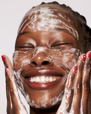 deep skin toned model washing face with cherry dub gel cleanser with a plush lather