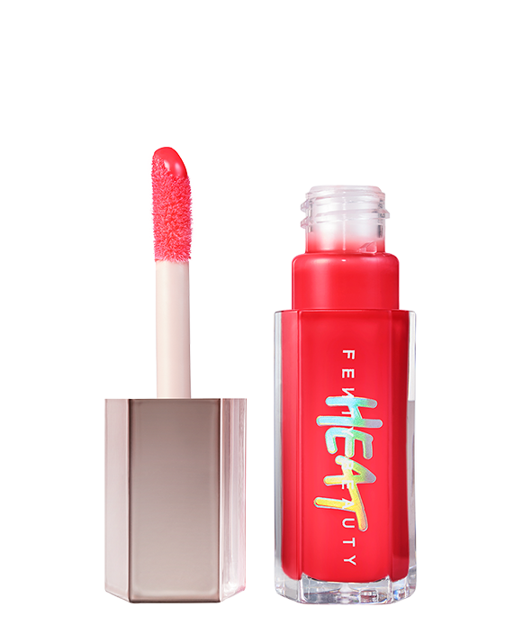 Closed tube of Gloss Bomb Heat lip gloss and plumper in the shade Hot Cherry on a grey background.