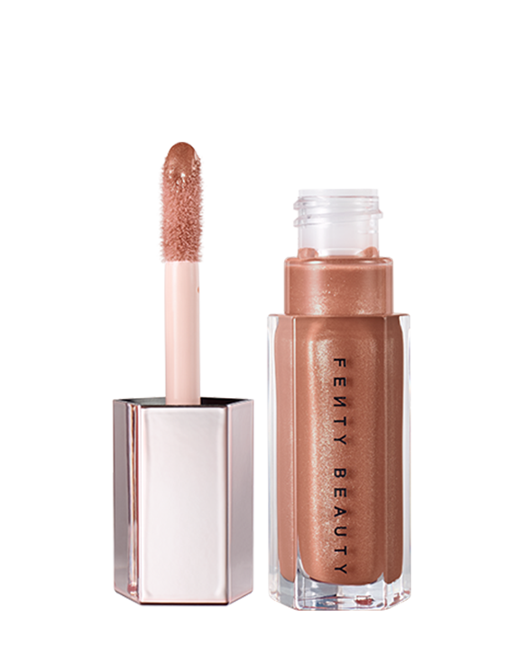 A closed tube of Gloss Bomb Universal Lip Luminizer in the shade Fenty Glow on a grey background.