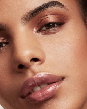 Close up of medium deep skin-toned model wearing Pro Kiss'r Luscious Lip Balm in shade Pinch Me.