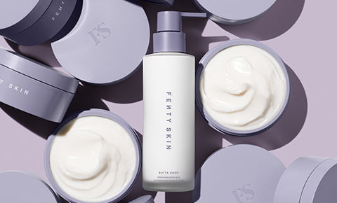 Editorial shot of Butta Drop Body Milk in the middle of two open Butta Drop Whipped Oil Body Cream containers.