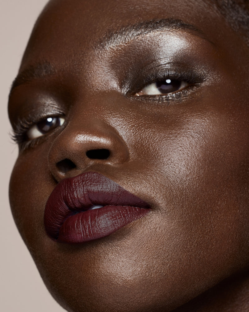 deep skin toned model wearing stunna lip paint in the shade underdawg