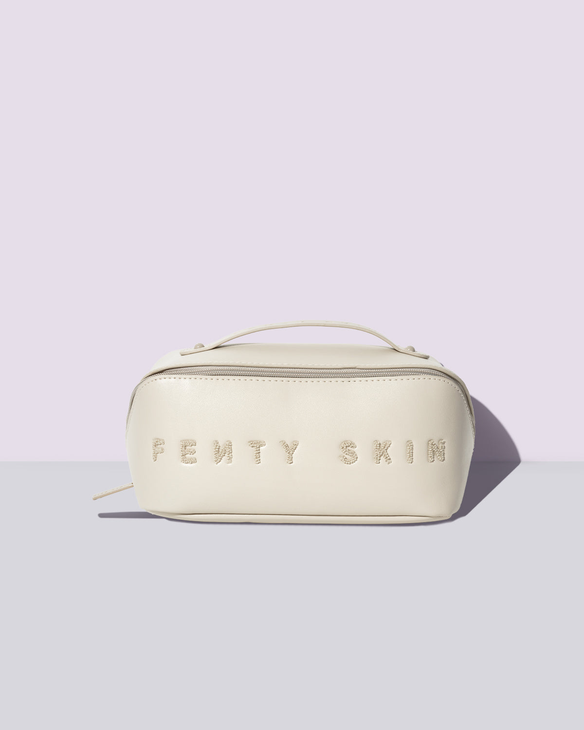 Cream Fenty Skin embossed makeup bag on a lavender background