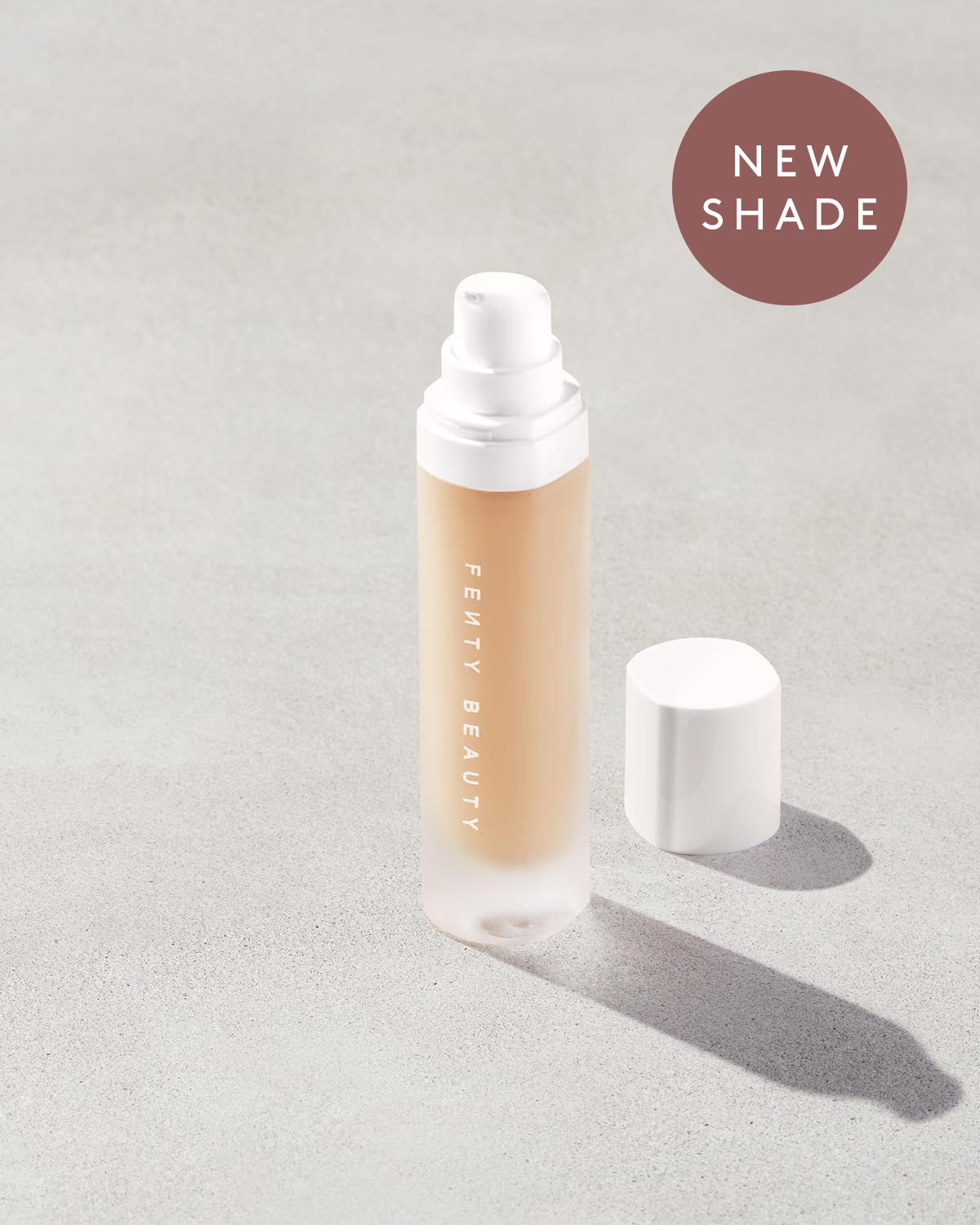 open bottle of Fenty Beauty Pro Filt'r Soft Matte Longwear Foundation with pump dispenser in shade #175 on concrete background