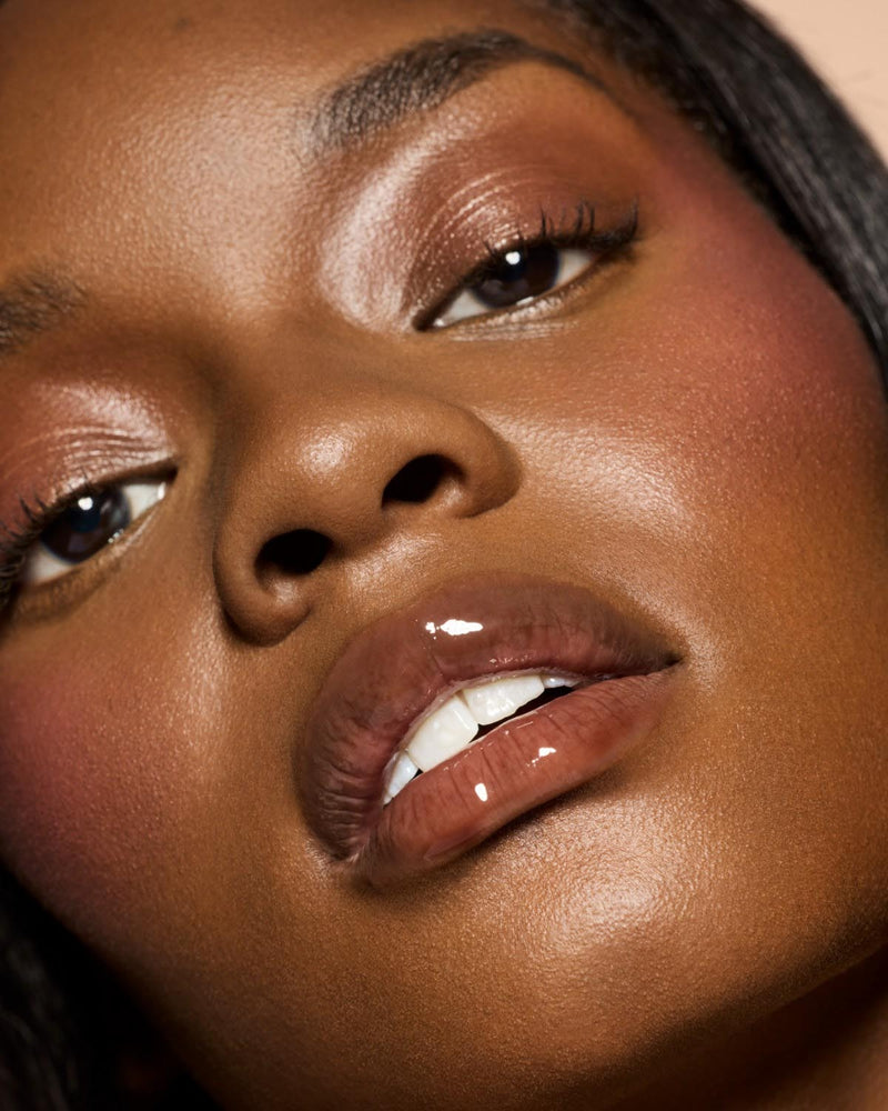 deep skin tone model wearing Gloss Bomb Heat Universal Lip Luminizer + Plumper in shade Hot Chocolit Heat