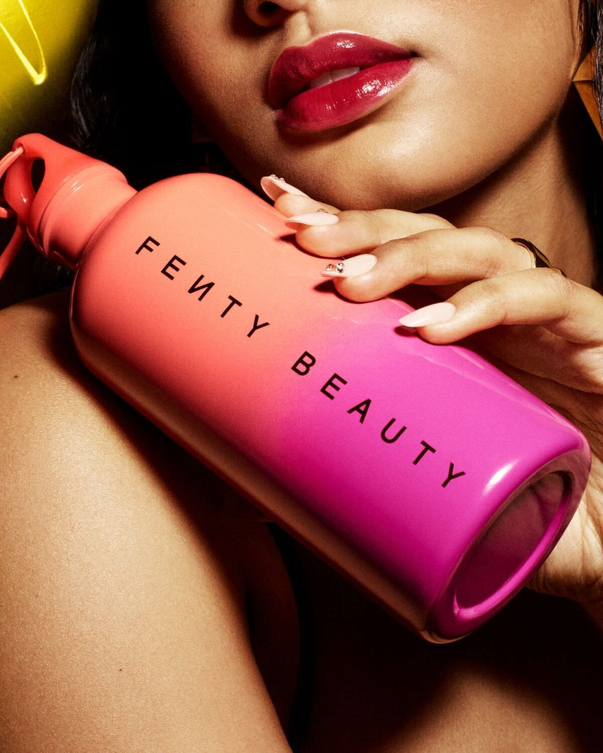 Model holding the Fenty Beauty Summatime 500 ml aluminum bottle.