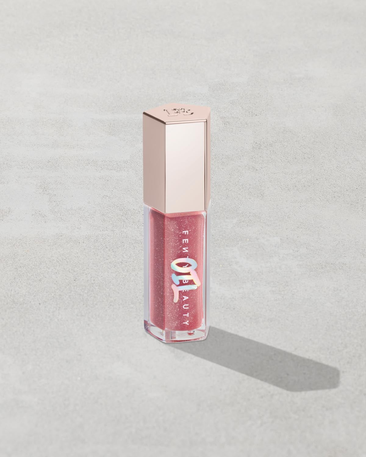 Gloss Bomb Oil Luminizing Oil and  Gloss in shade Fussy product against a concrete background.