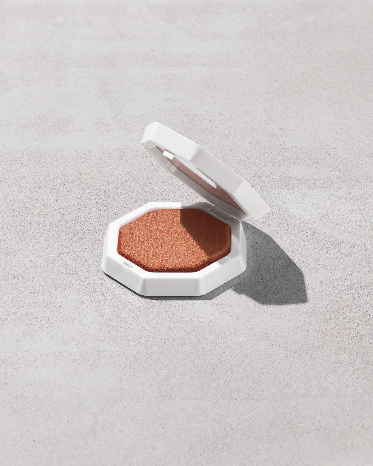 Open product shot of Demi'glow Light-Diffusing Highlighter in shade That's Rich on a concrete backdrop.