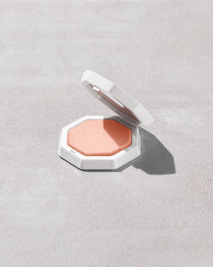 Open product shot of Demi'glow Light-Diffusing Highlighter in shade Tutu Much on a concrete backdrop.