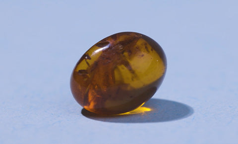 Ingredient image of golden amber on a lavender background.