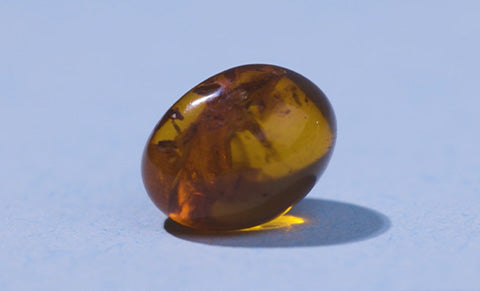 Ingredient image of golden amber on a lavender background.
