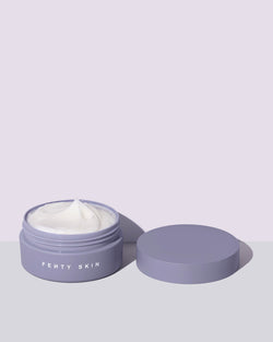 An open tub of a travel size Butta Drop Whipped Oil Body Cream with Tropical Oils + Shea Butter on a lilac background.