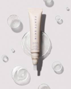 Open tube of Blemish Defeat'r BHA Spot-Targeting Gel against a light backdrop surrounded by drops of the product.