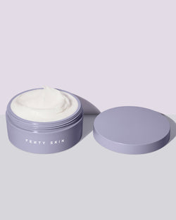 An open tub of Butta Drop Whipped Oil Body Cream with Tropical Oils + Shea Butter on a lilac background.