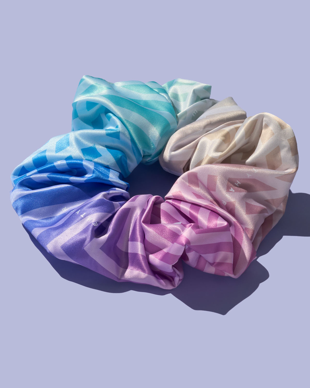 Fenty hair rainbow scrunchie on a lavender backgroud