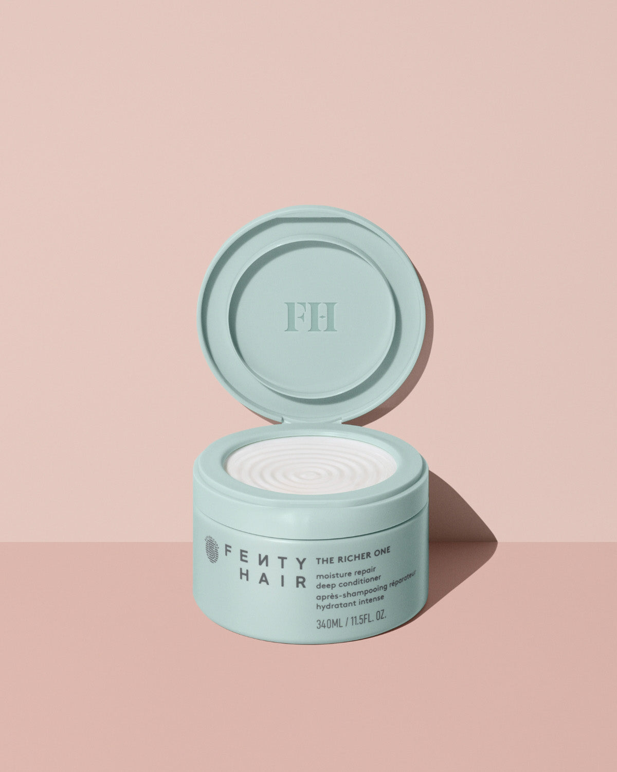 Fenty Hair The Richer One Moisture Repair Deep Conditioner tub made of 50% post-consumer recycled plastic on a pink background.