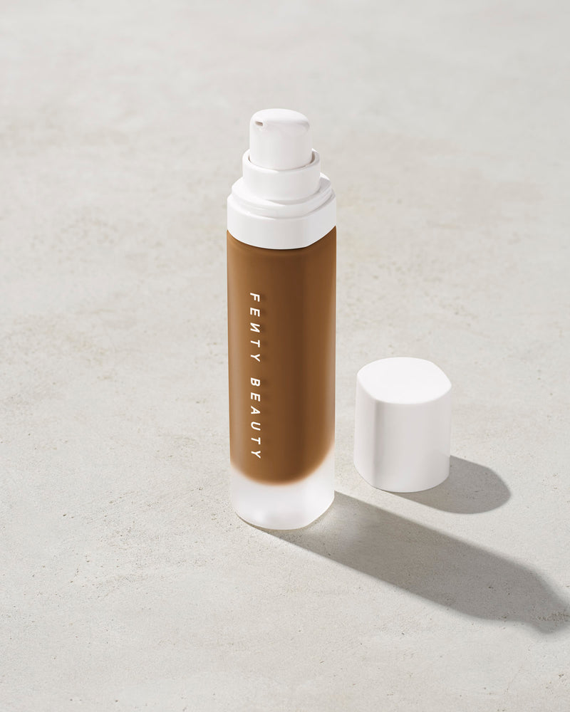 open bottle of Fenty Beauty Pro Filt'r Soft Matte Longwear Foundation with pump dispenser in shade 445 on concrete background