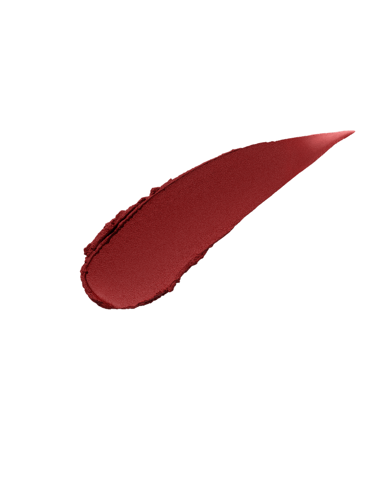  A smear of Fenty Icon Velvet lipstick in brick red color on a light background.