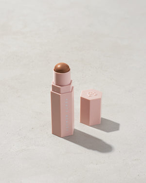 Match Stix Contour Skinstick shown in shade Mocha on a concrete background. 