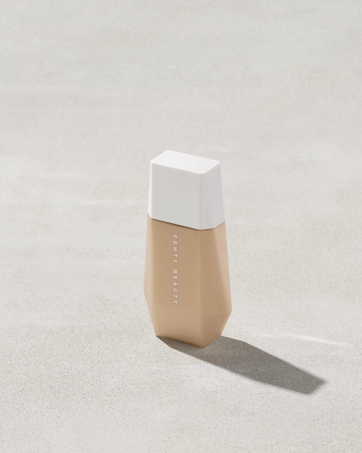 A bottle of Eaze Drop Blurring Skin Tint in shade 8 on a grey backdrop.