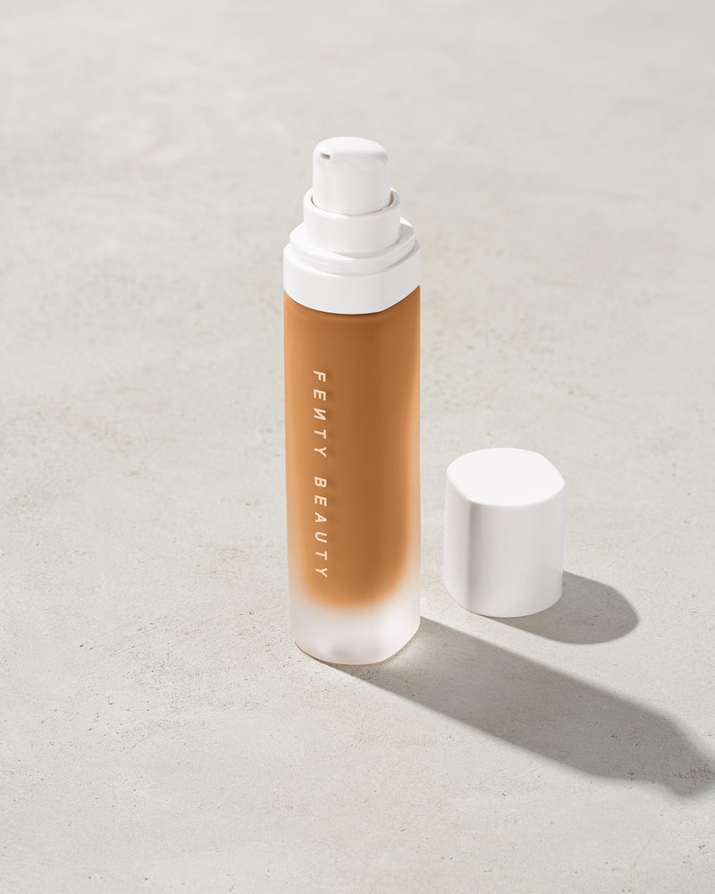 open bottle of Fenty Beauty Pro Filt'r Soft Matte Longwear Foundation with pump dispenser in shade 390 on concrete background