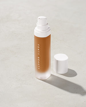 open bottle of Fenty Beauty Pro Filt'r Soft Matte Longwear Foundation with pump dispenser in shade 410 on concrete background