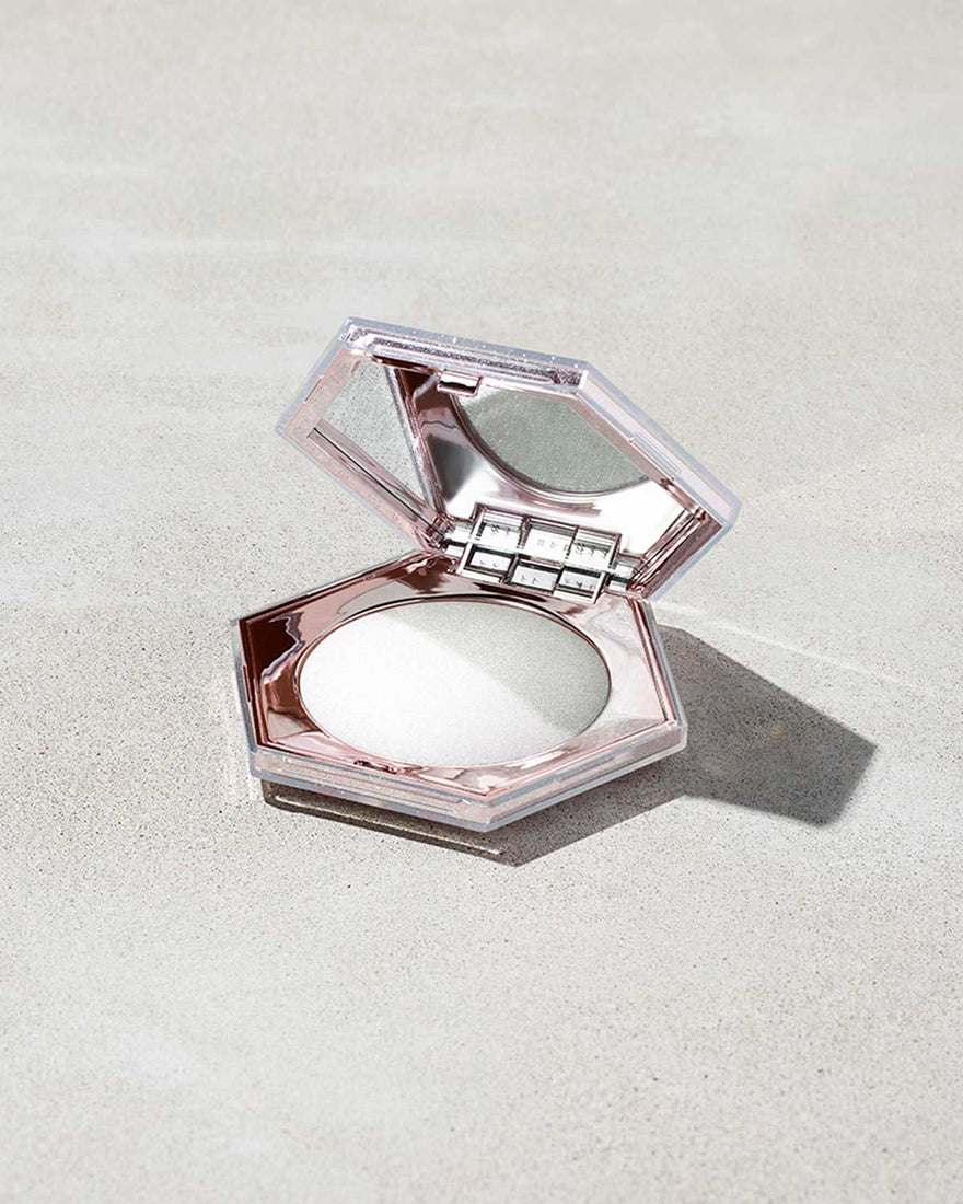 Open compact of the Diamond Bomb All-Over Highlighter in How Many Carats?! shade on a marbled background.