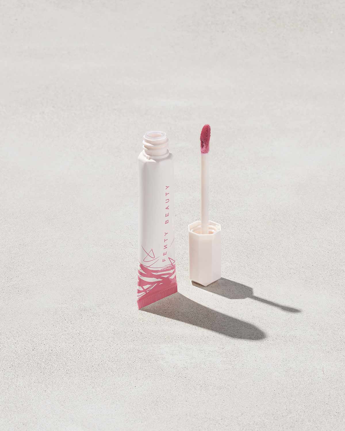 Open tube of Pro Kiss'r Luscious Lip Balm in shade Pinch Me on grey background.