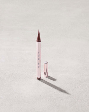 Fenty Beauty Flyliner Longwear Liquid Eyeliner in shade In Big Truffle with cap off on concrete background