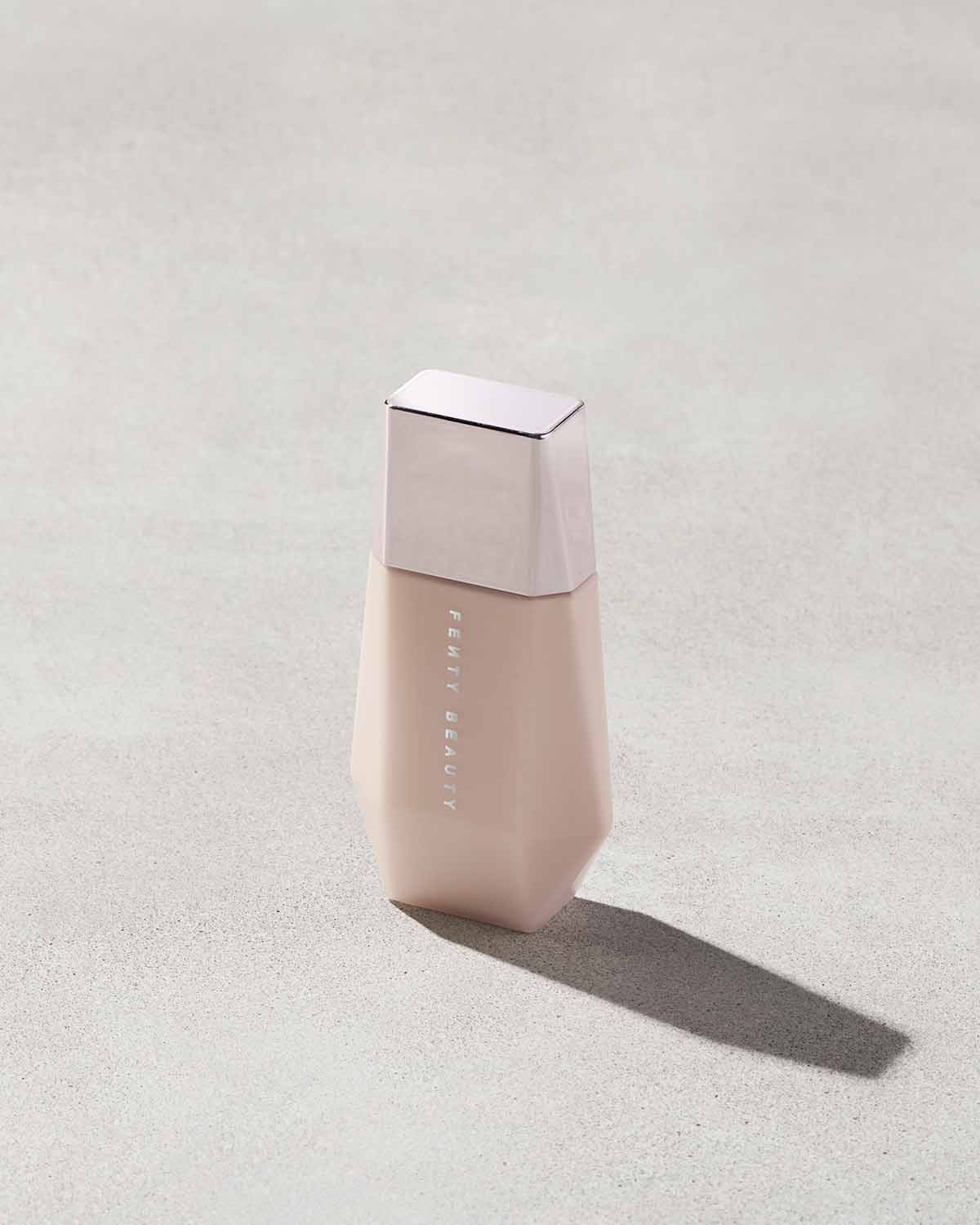 Eaze Drop’Lit All-Over Glow Enhancer shown in shade Pink Pearl on a concrete background. 